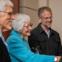 A woman smiles and shakes hands with other guests